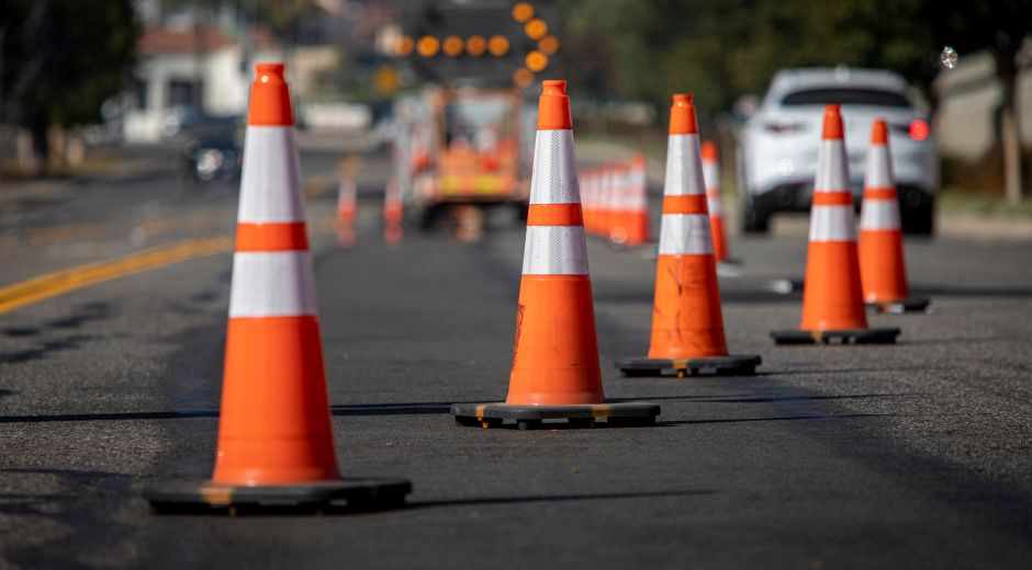 Row of orange traffic control cones lining a road at an active construction zone.